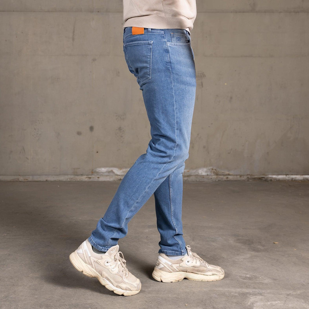 Zijaanzicht van een model in The Slim jeans van Delft Denim – een duurzame slim-fit heren spijkerbroek. Gemaakt van biologisch en gerecycled katoen voor een perfecte pasvorm.