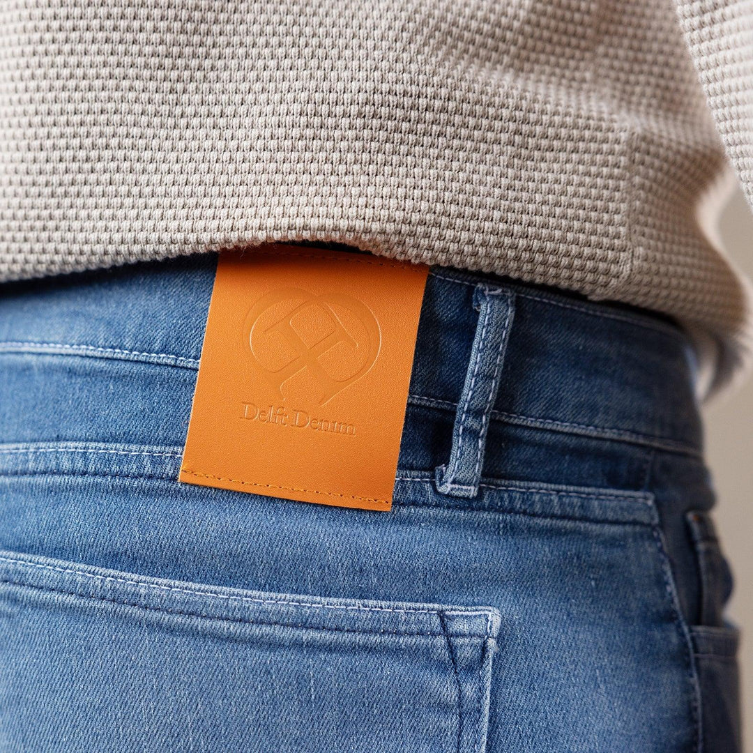 Detail van The Slim jeans van Delft Denim – close-up van de leren patch met logo. Duurzame heren spijkerbroek van biologisch en gerecycled katoen met premium afwerking.