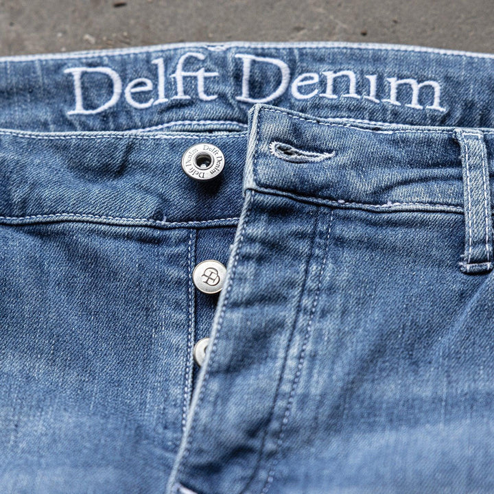 Detail van The Straight jeans van Delft Denim – duurzame slim-fit spijkerbroek met knoopsluiting en geborduurd logo. Gemaakt van biologisch en gerecycled katoen voor comfort.